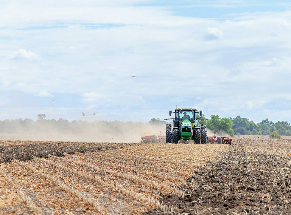 A tractor driving through a dry field